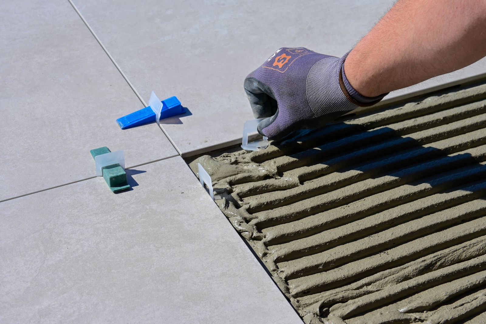 Main gantée qui aligne des carreaux de sol avec des croisillons