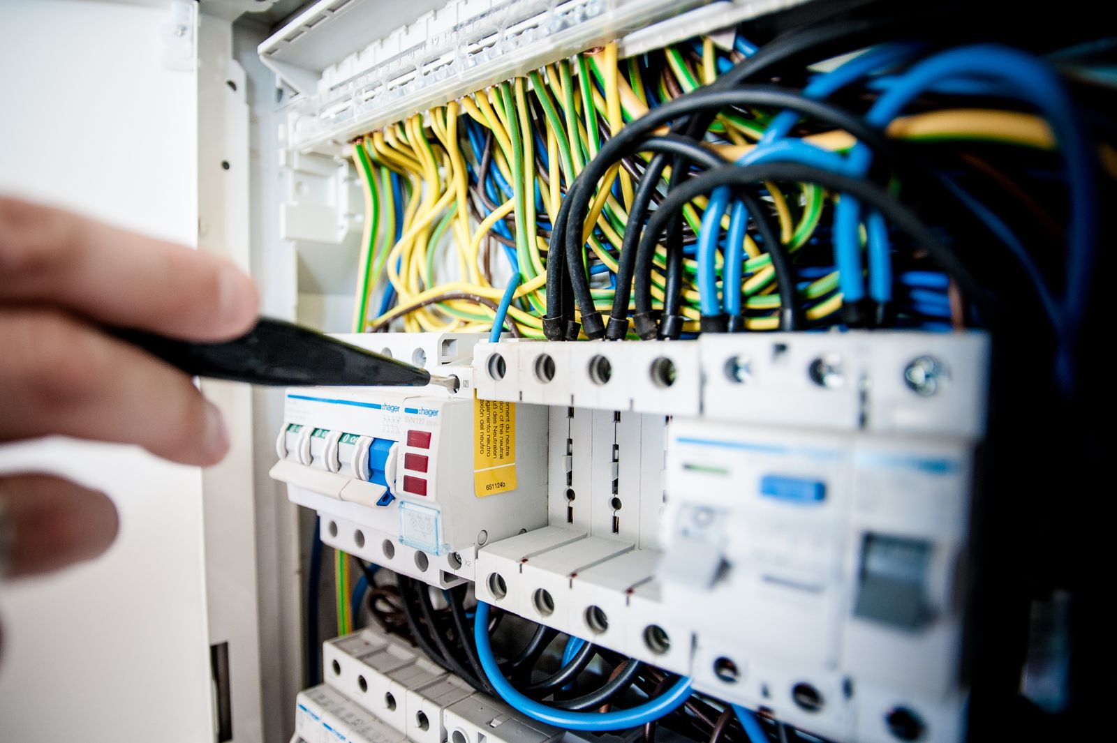 Main d'un électricien sur les disjoncteurs d'un tableau électrique