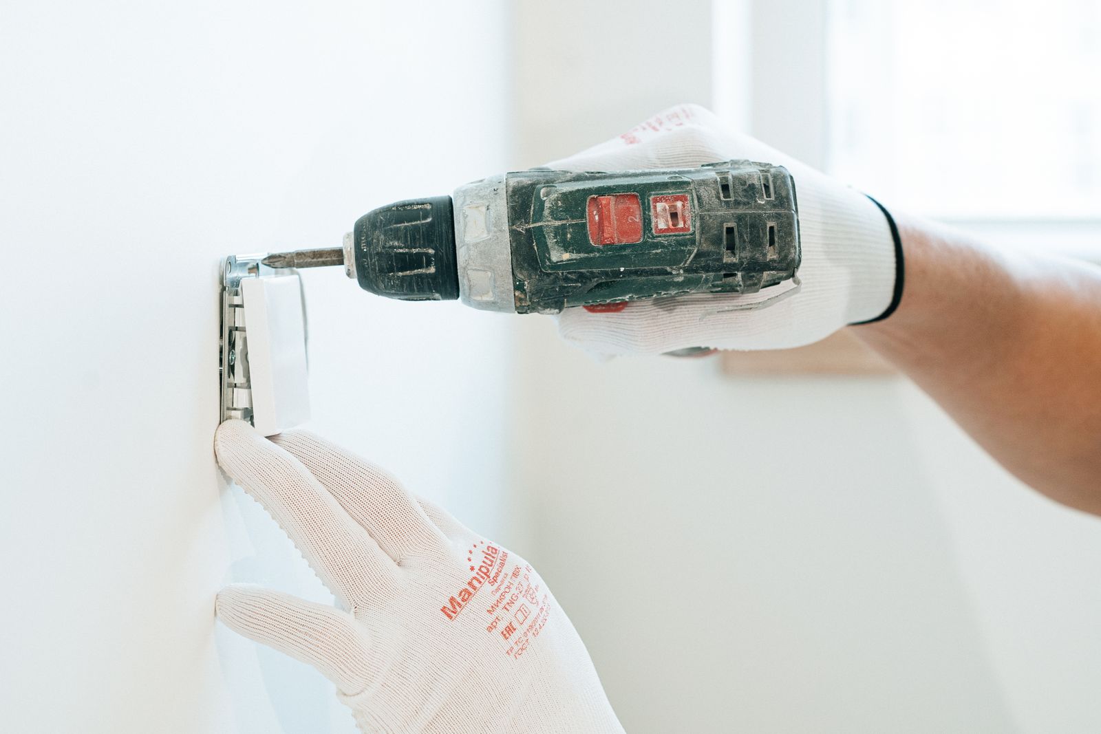 Mains gantées perçant un mur avec une perceuse sans fil