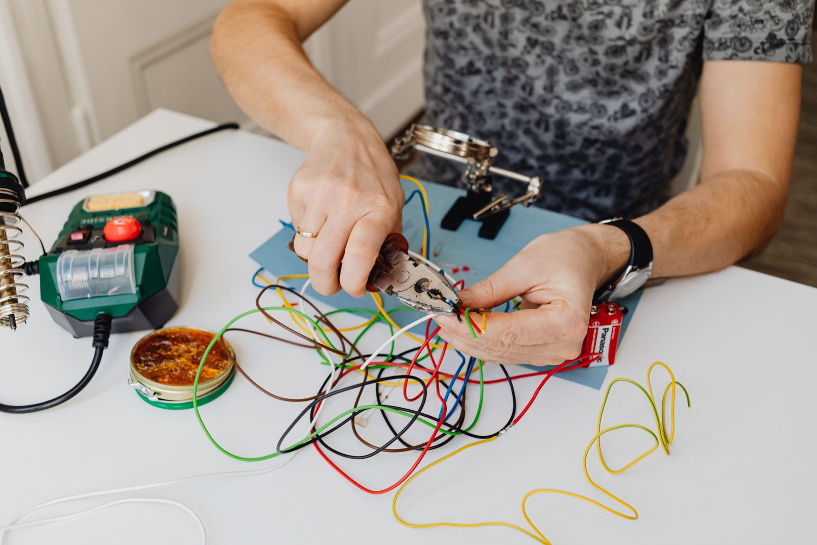 Mains dénudant des fils électriques colorés avec une pince